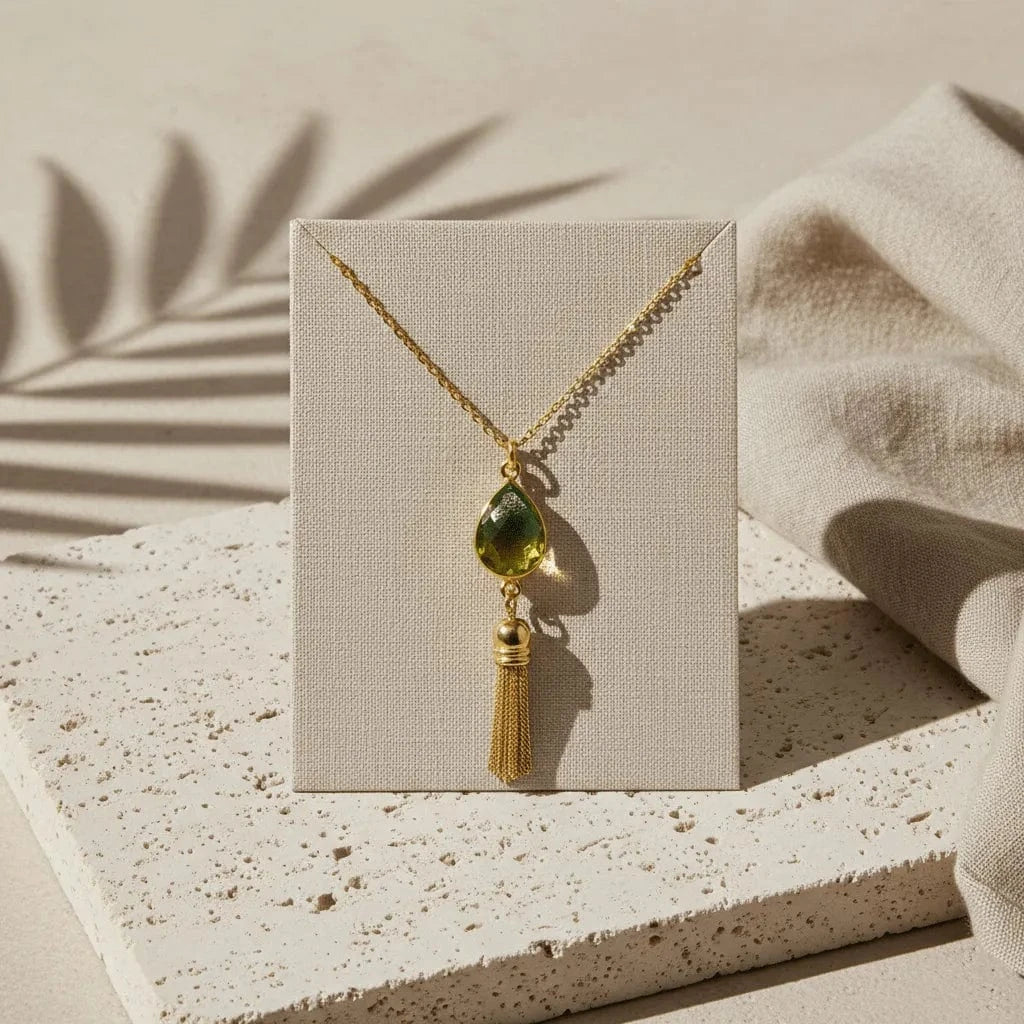 Necklace with a teardrop-shaped pendant and gold tassel on a white background