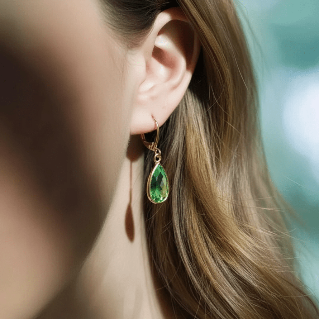 Close-up of a woman wearing a green teardrop earring with a blurred background