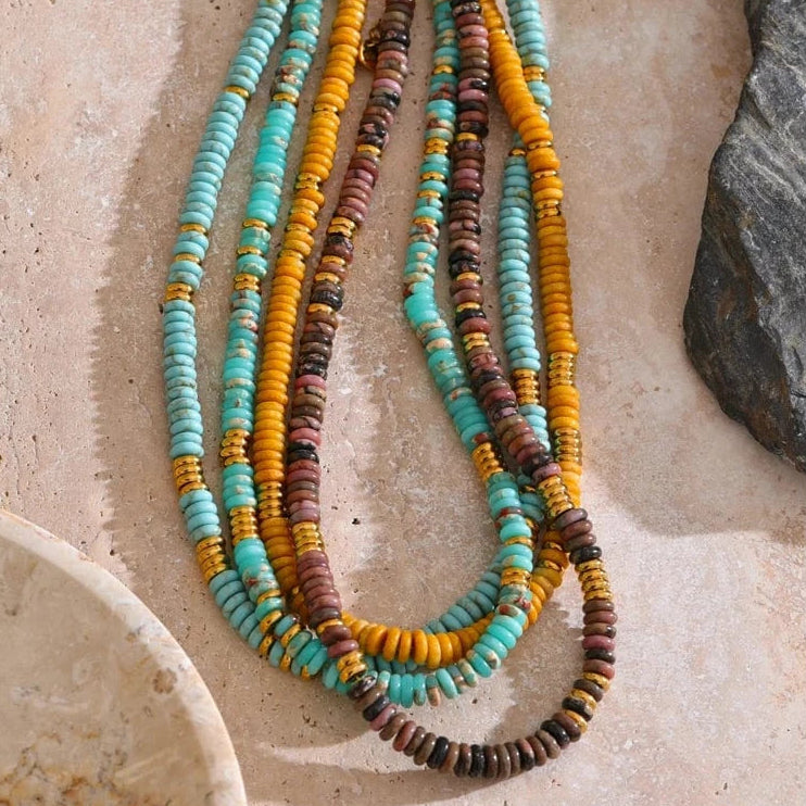 Multicolored beaded necklace on a textured stone surface