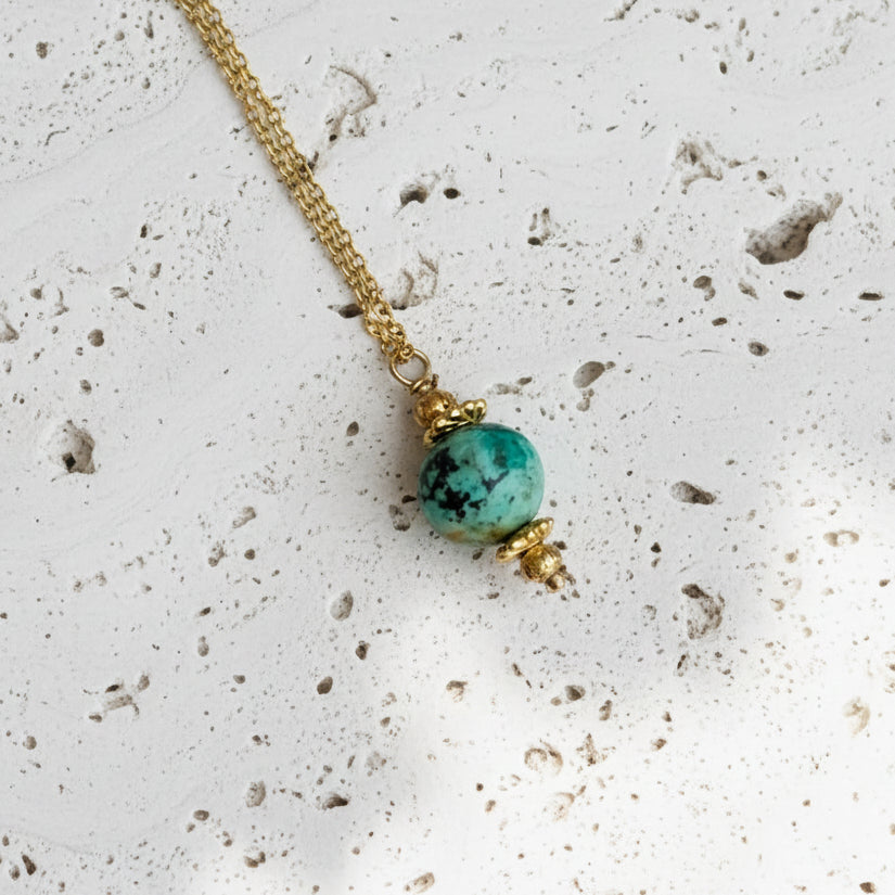 Necklace with a turquoise bead on a white background