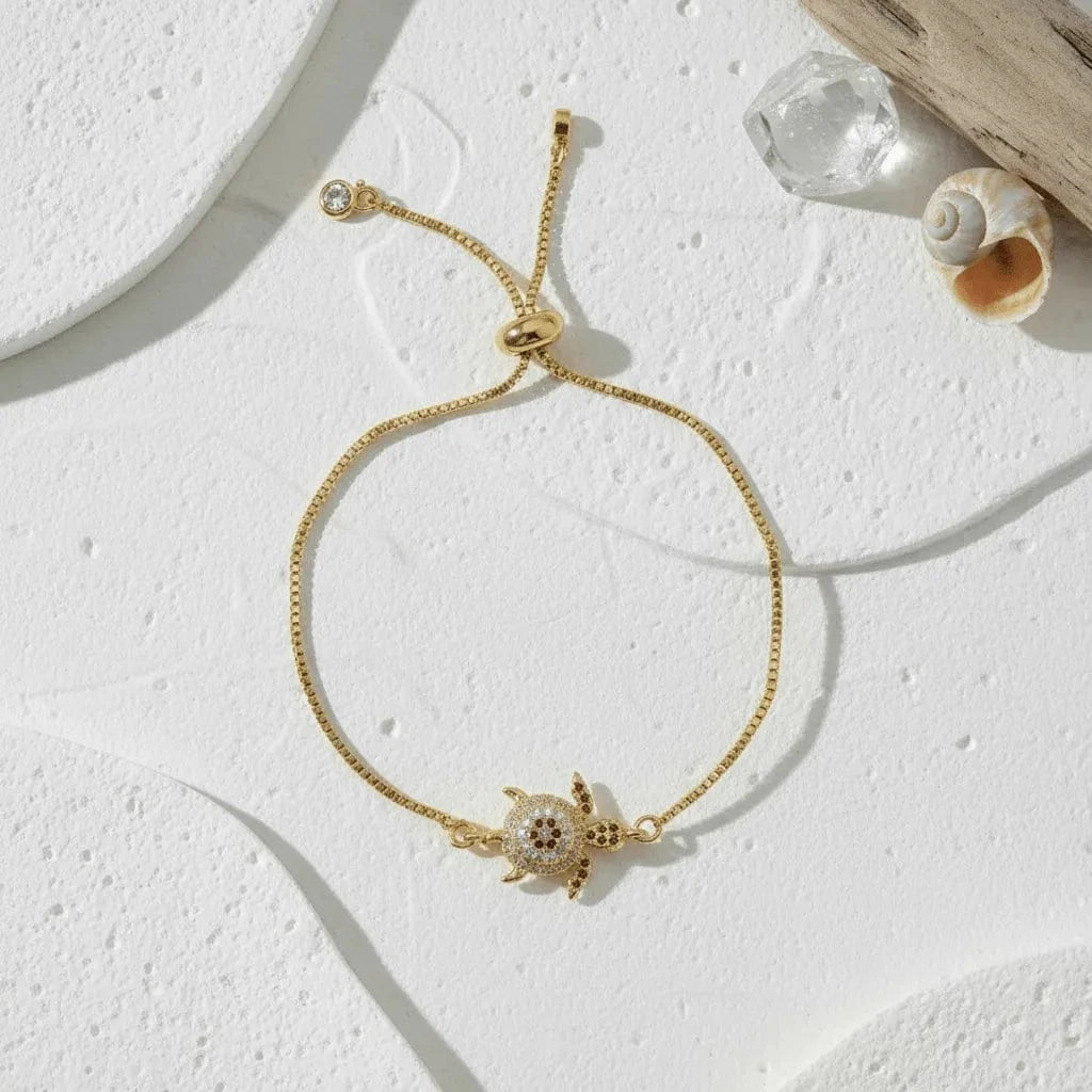 Gold bracelet with a turtle charm on a light background