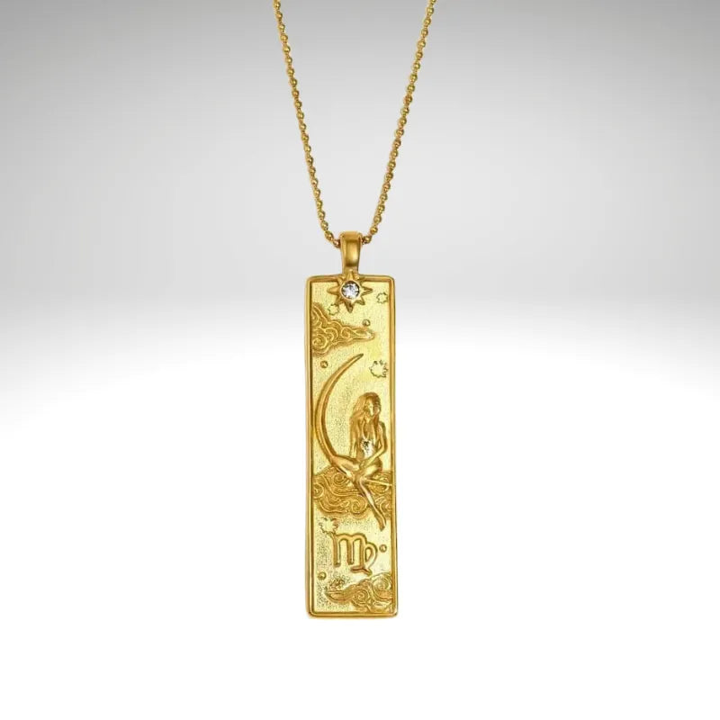 Gold pendant with intricate design on a chain against a light gray background