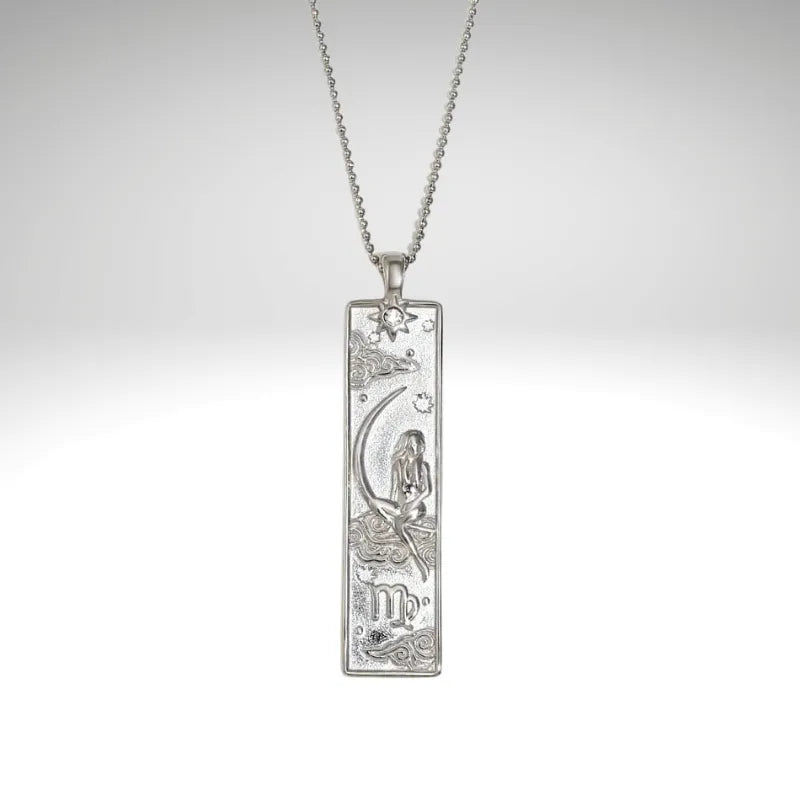 Silver pendant with zodiac design on a chain against a light gray background