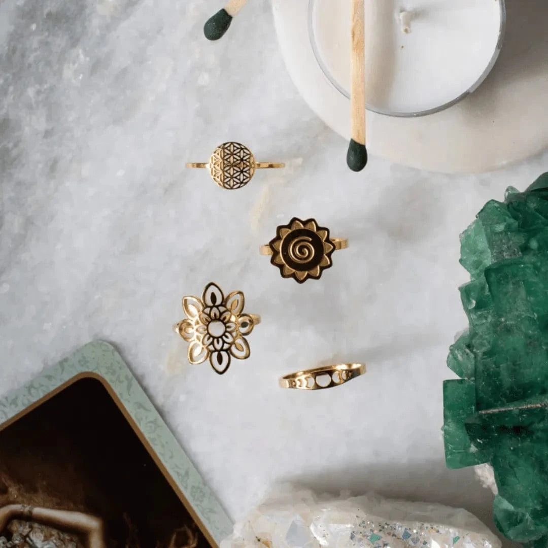 Gold rings on a marble surface with a candle and crystal