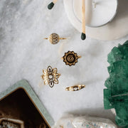 Gold rings on a marble surface with a candle and crystal