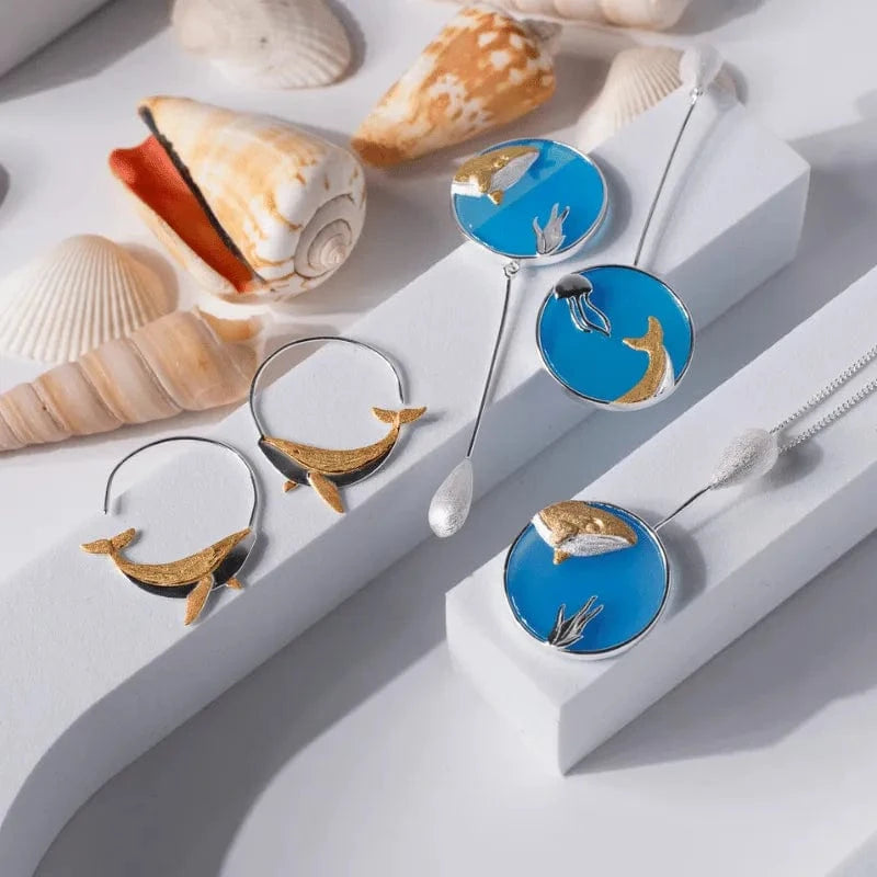 Spoon with whale design on a white surface with seashells