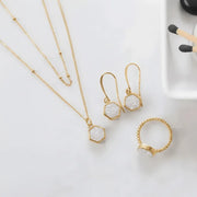Gold jewelry set with necklace, earrings, and ring on a white surface