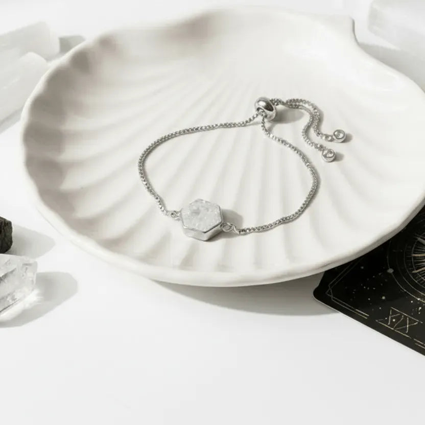 Silver bracelet with a hexagonal stone on a white scallop shell