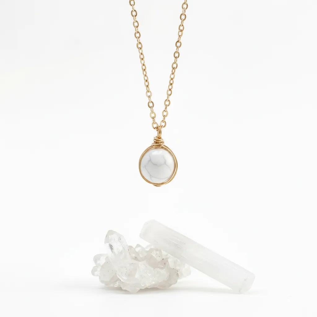 Necklace with a white pendant and gold chain on a white background