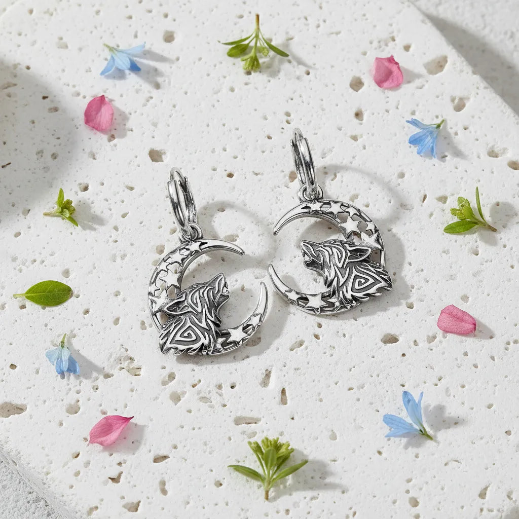 Silver wolf and moon pendant on a textured white surface with small flowers and leaves.