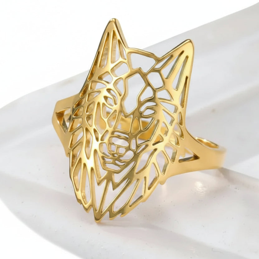 Gold wolf head ring on a white fabric background