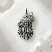 Silver wolf head pendant on a white marble surface