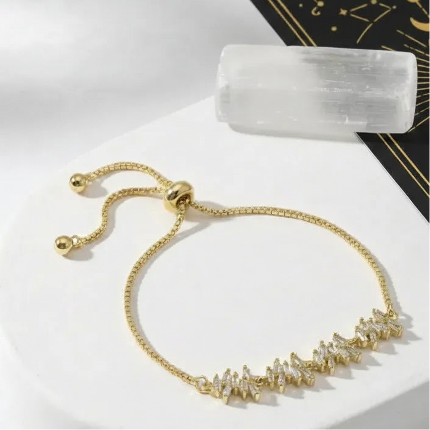 Gold bracelet with crystals on a white surface, tarot card, and crystal  